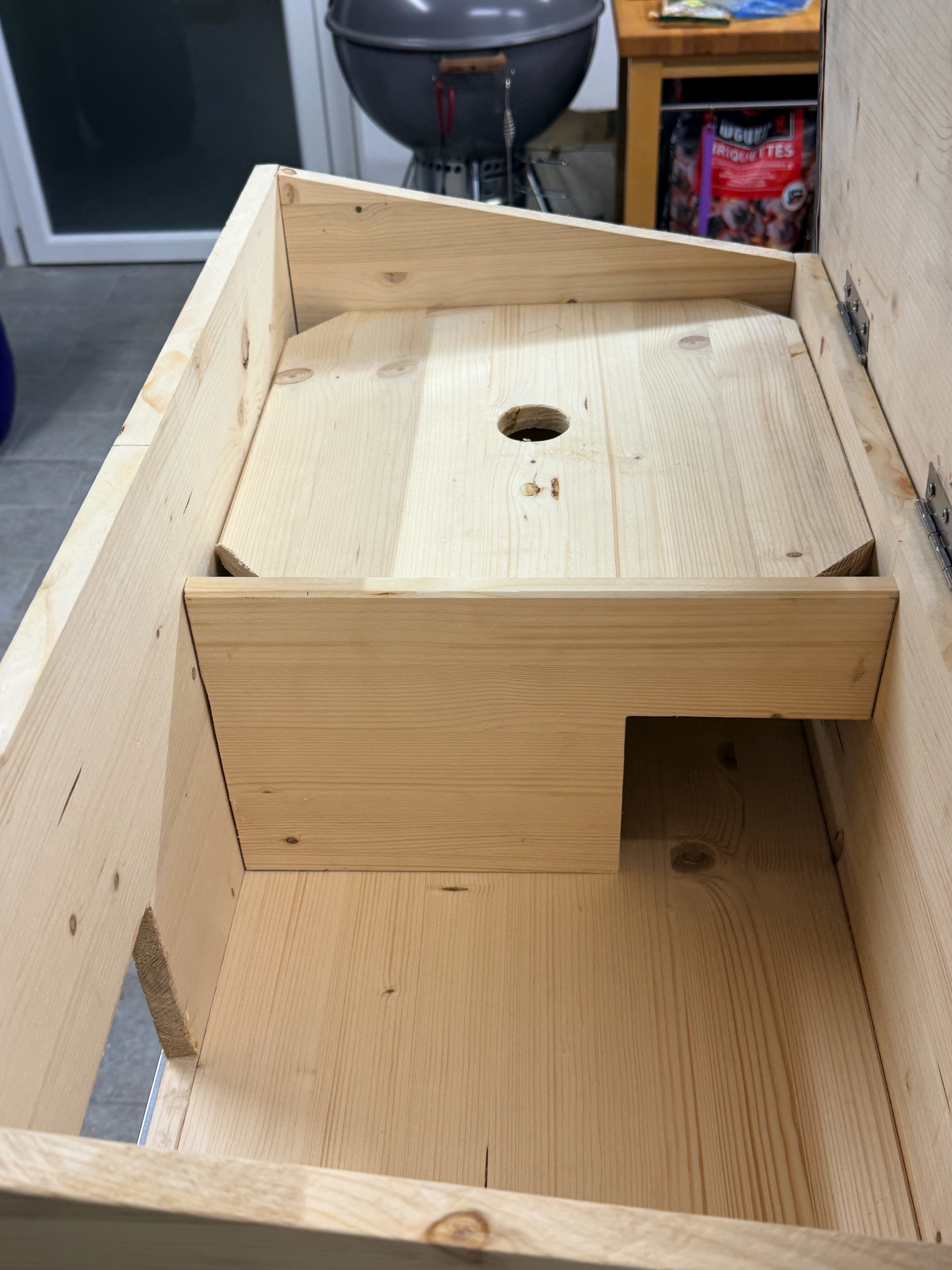 Loose wood nest lid with finger hole and clipped corners resting over the sleeping chamber
